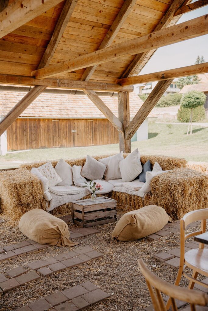 Lounge mit Strohballen, Kissen und Sitzsäcken unter dem Holzpavillon