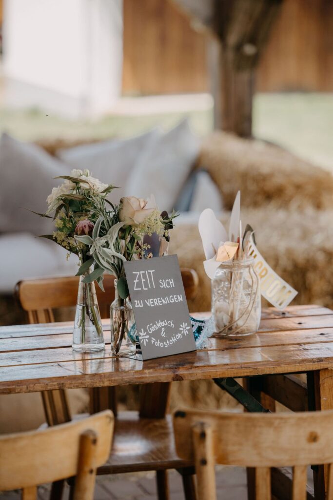 Holztisch mit Wildblumen und Schild bei der Holler Scheune