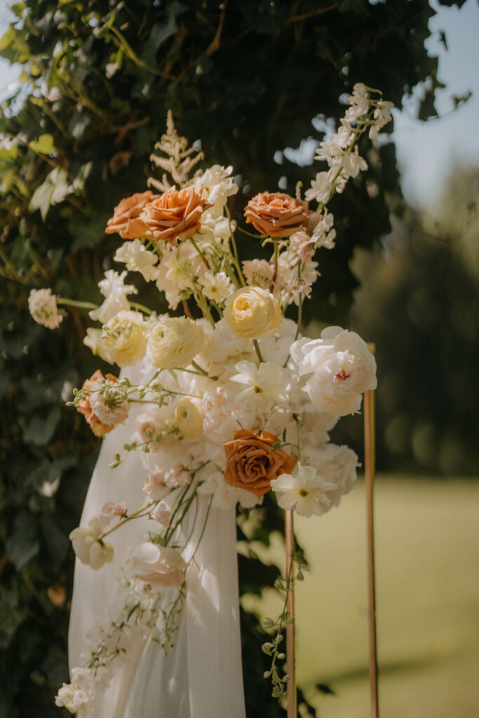 Nahaufnahme vom Blumenschmuck am Traubogen – Rosen in Apricot, Weiß und Pfirsich
