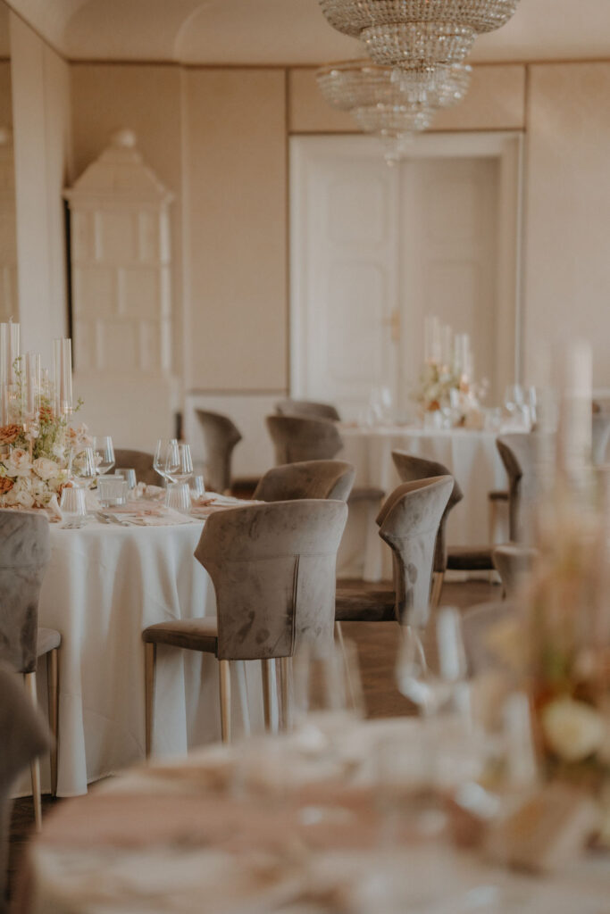 Elegante Hochzeitstafel im Festsaal von Aiola im Schloss St. Veit – gedeckt mit Blumen und Kristallgläsern