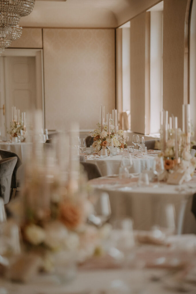 Festlich gedeckter Hochzeitssaal mit runden Tischen, Blumenschmuck und Kerzen im stilvollen Ambiente des Schlosses