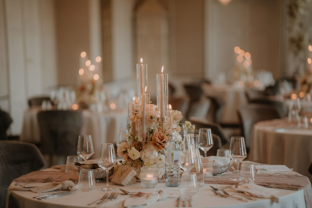 Abendliche Hochzeits-Tischdekoration mit stimmungsvoller Beleuchtung, Blumenarrangement und Kerzen im Schloss St. Veit