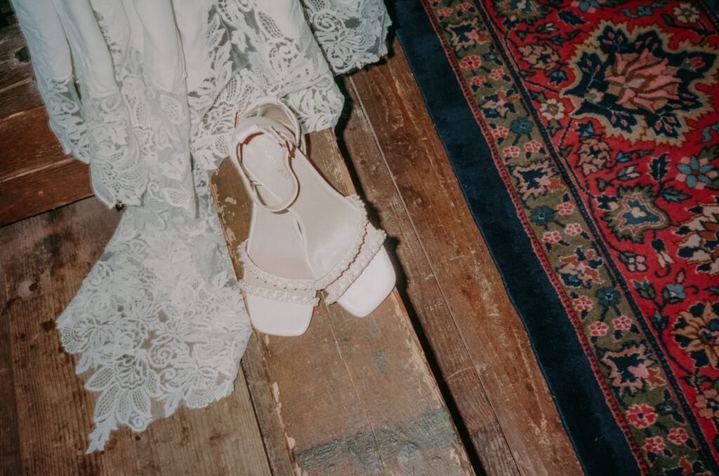 Elegante Brautschuhe mit Perlen-Details auf altem Holzboden – romantisch inszeniert im Vintage-Stil auf Portra 400.