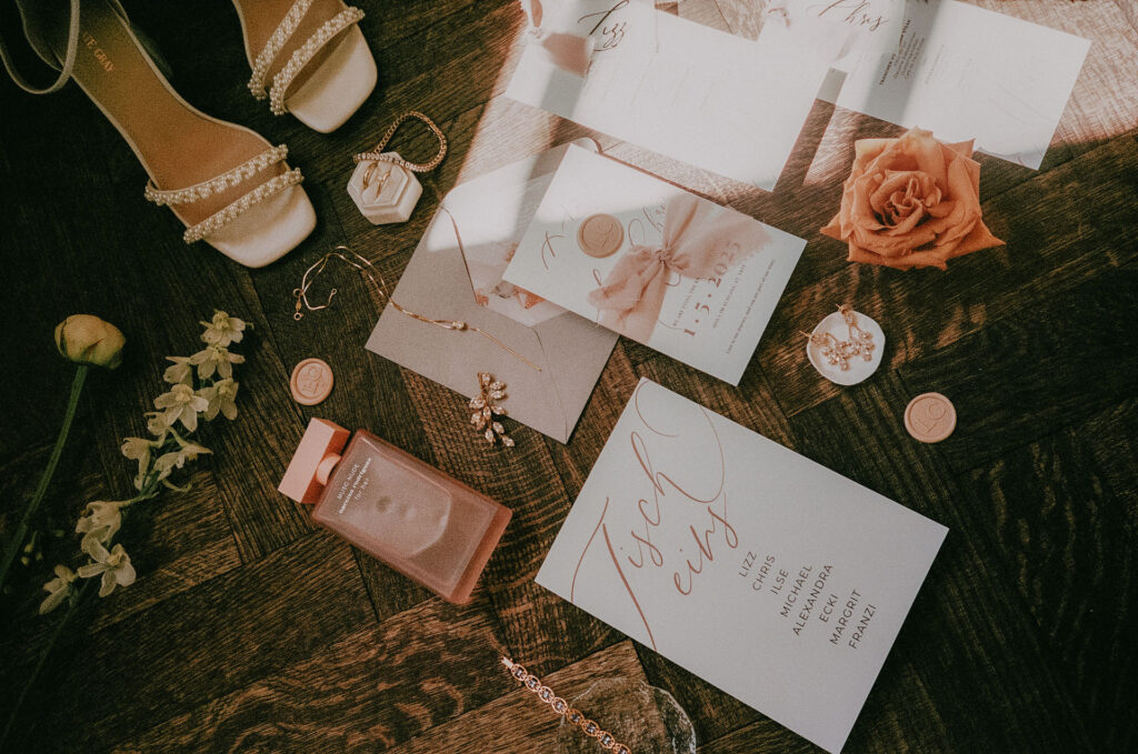Flatlay mit Hochzeitspapeterie, Schmuck, Parfum und Brautschuhen – elegant in Szene gesetzt auf analogem Film.