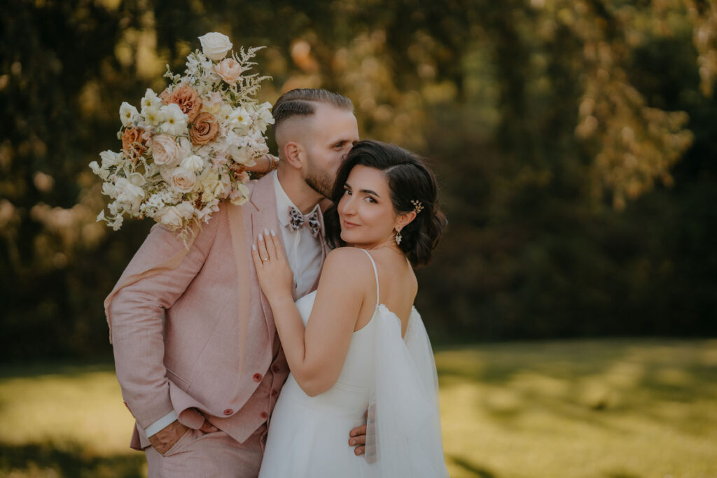 Detailaufnahme: Braut Lizz und Bräutigam Chris mit Brautstrauß in Rosé- und Cremetönen.