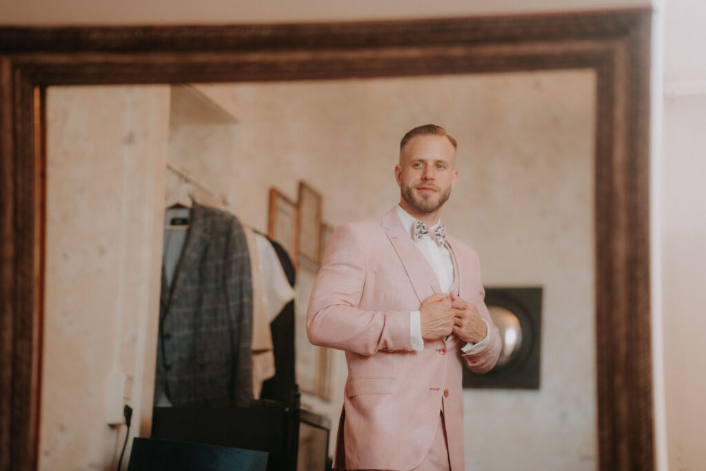 Chris im rosa Hochzeitsanzug – modisches Highlight und Überraschung für Braut Lizz, aufgenommen beim Getting Ready.