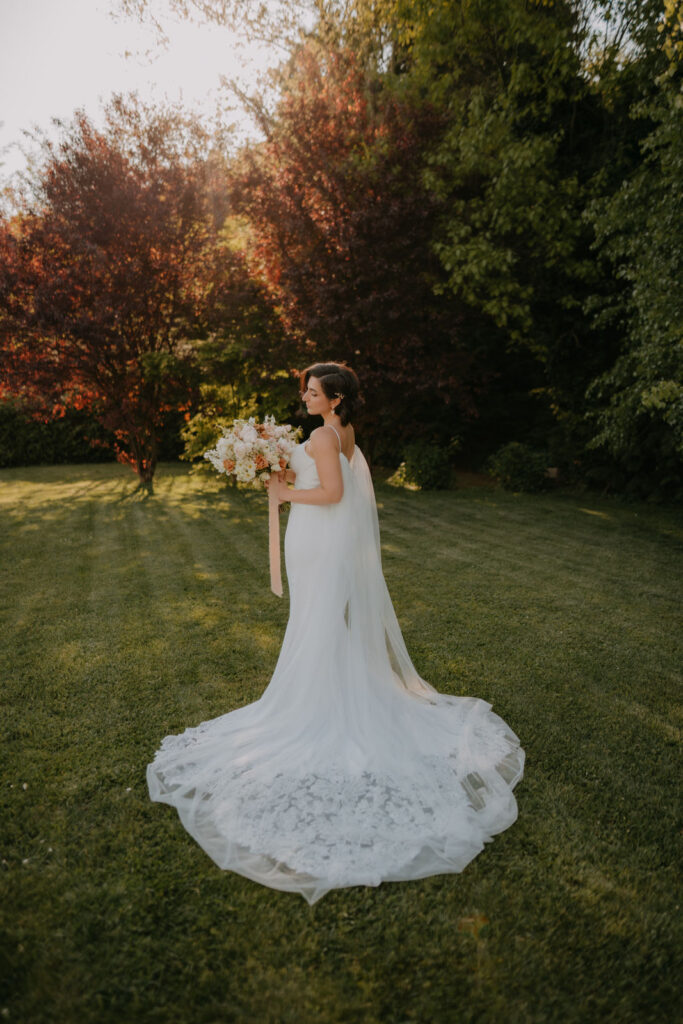 Braut Lizz mit fließendem Brautkleid und elegantem Schleier – aufgenommen in der Abendsonne.