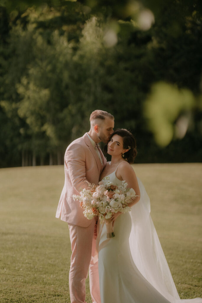 Lizz und Chris während ihres Paarshootings – inniger Moment auf der sonnigen Wiese der Hochzeitslocation.