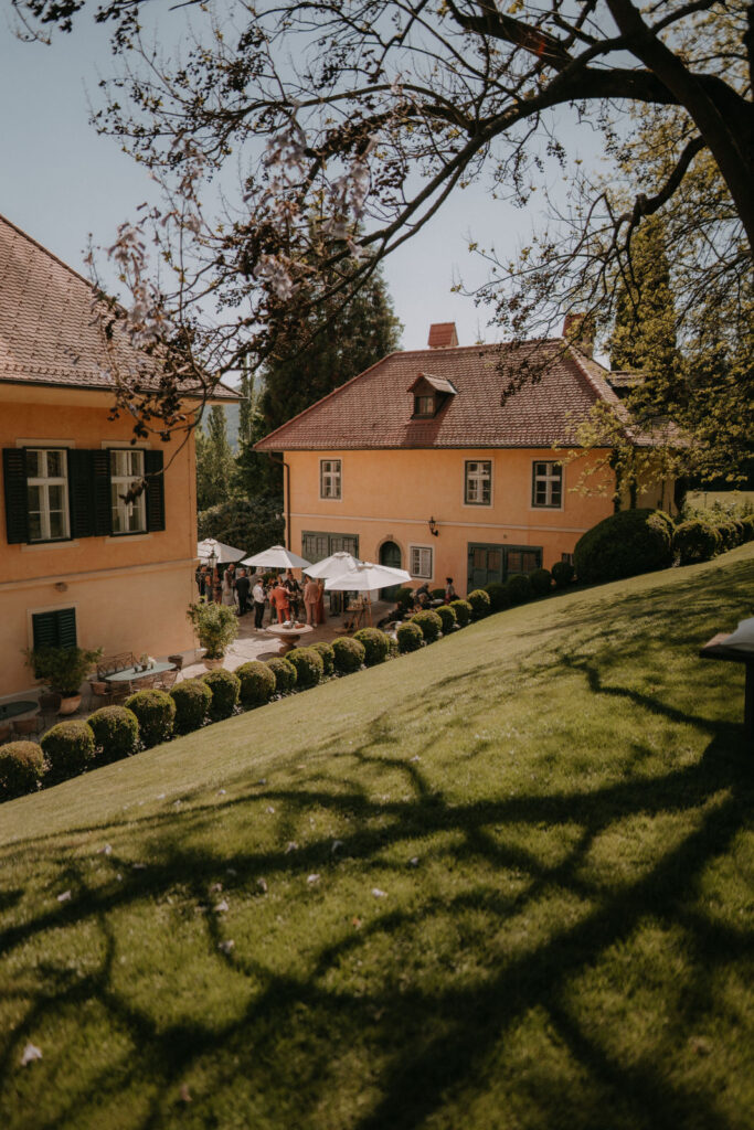 Schlossgarten von Aiola mit Gästen beim Sektempfang – Frühlingshochzeit in der Steiermark