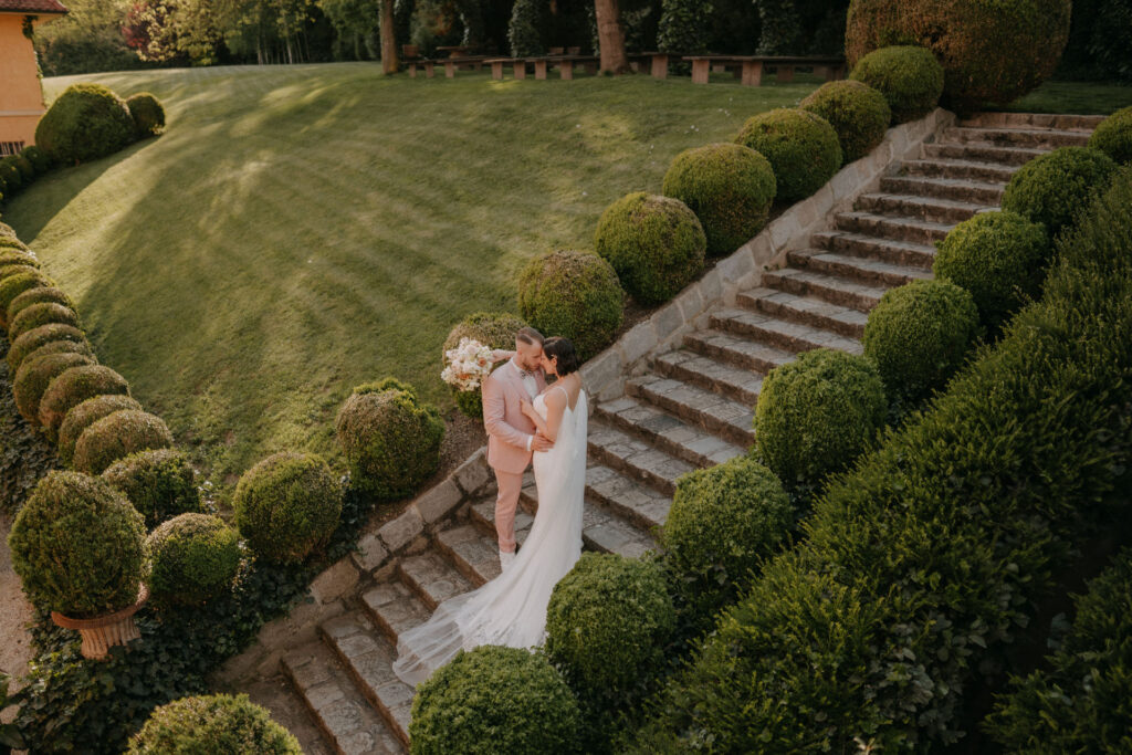 Intimer Moment auf der Steintreppe im Schlossgarten von Aiola – Brautpaar küsst sich