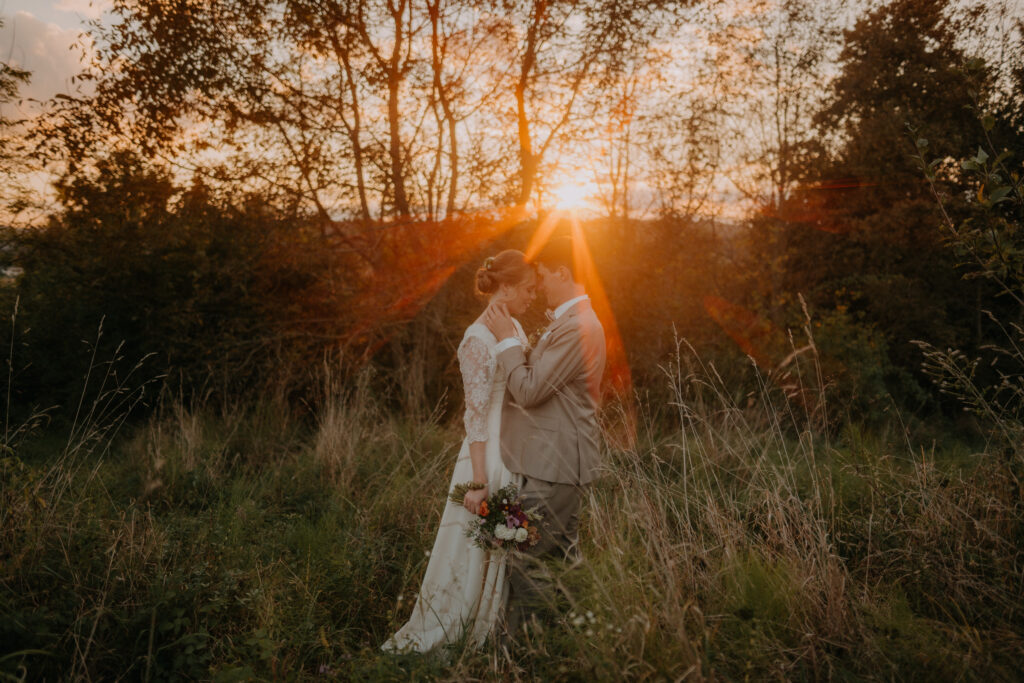Brautpaar im hohen Gras bei Sonnenuntergang – stimmungsvolles Hochzeitsfoto