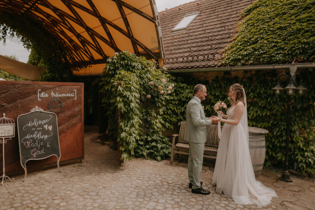 Emotionaler First Look des Brautpaars in einem Garten, sie lächeln sich an.