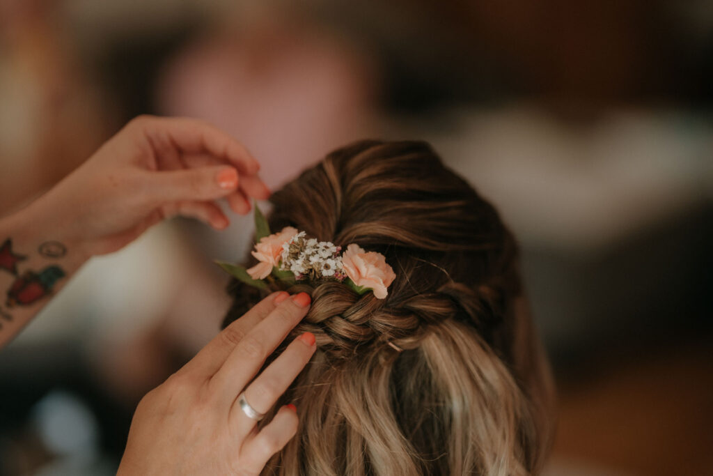 Haarstyling der Braut, floraler Haarschmuck wird ins Haar gesteckt.