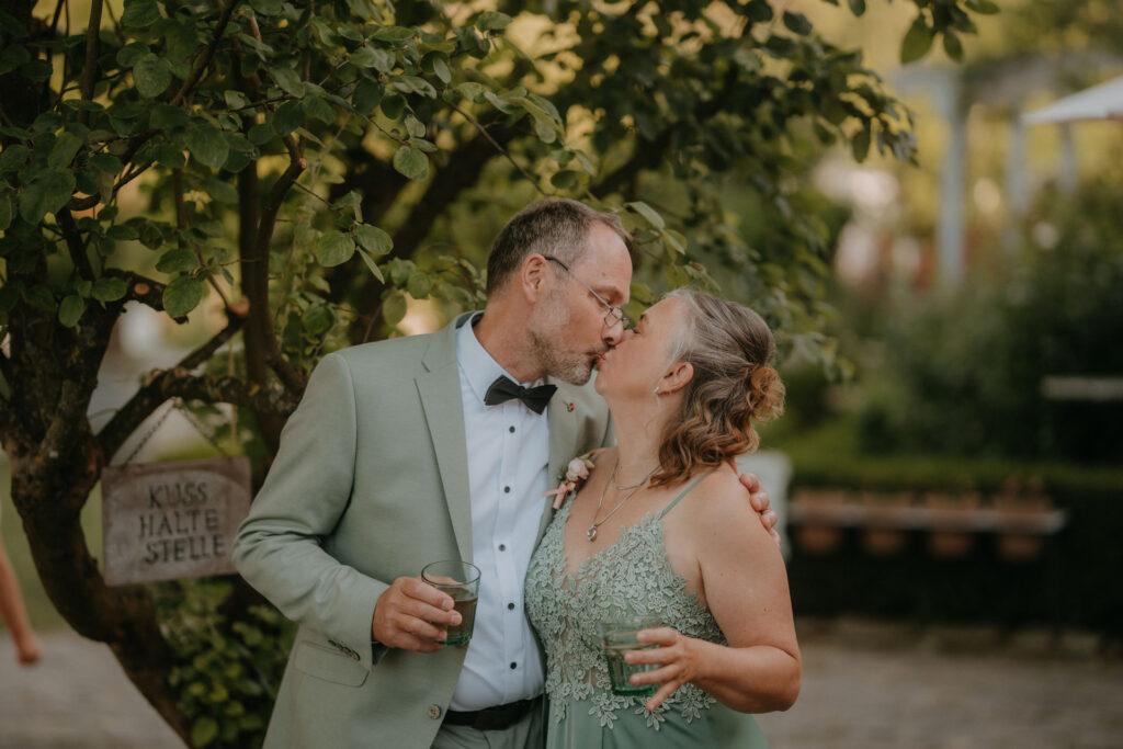 Romantischer Kuss eines eleganten Paars in festlicher Kleidung bei der Hochzeit.