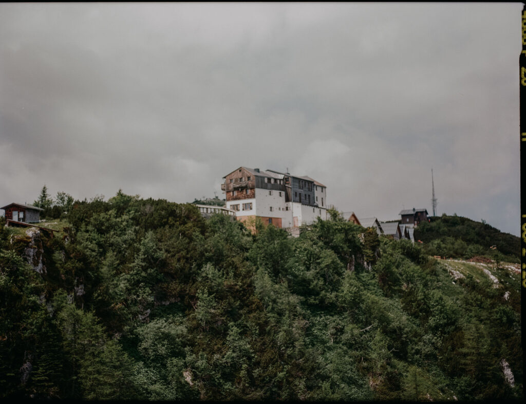 Blick auf die Feuerkogel-Bergstation mit umliegenden Hütten und viel grüner Vegetation an einem bewölkten Sommertag.