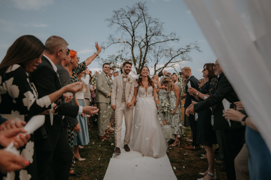 Brautpaar läuft durch ein Spalier aus Gästen nach der Trauung – emotionale Hochzeitsreportage in der Holler Scheune Steiermark