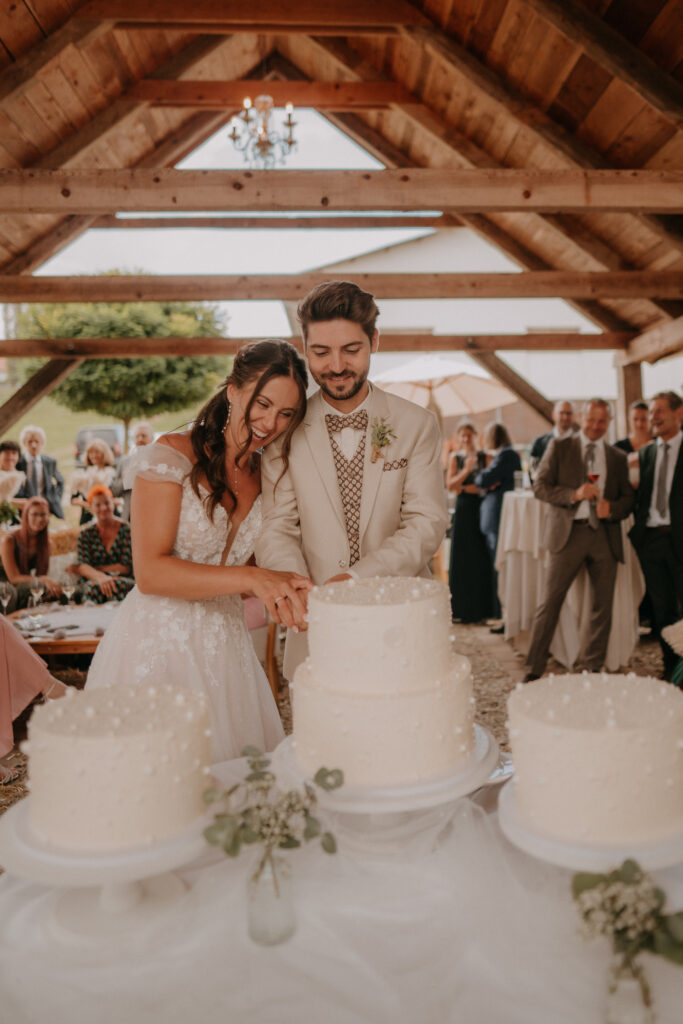 Brautpaar schneidet gemeinsam die Hochzeitstorte an – emotionale Hochzeitsreportage in der Holler Scheune Südsteiermark