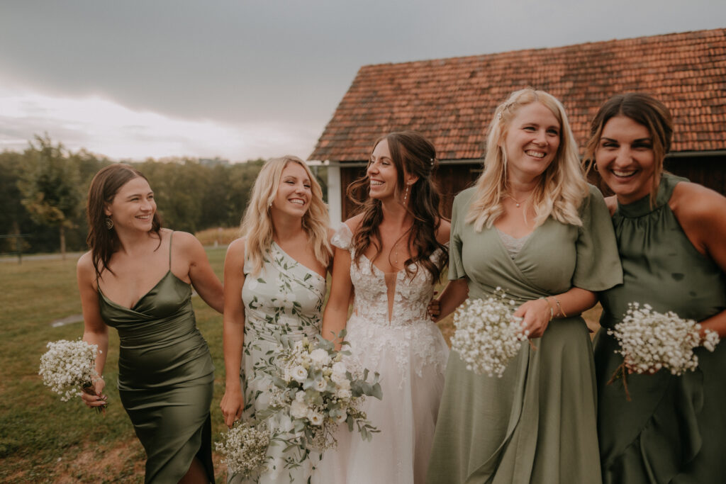 Braut mit ihren Freundinnen lacht im Abendlicht – authentische und natürliche Hochzeitsfotografie in der Steiermark
