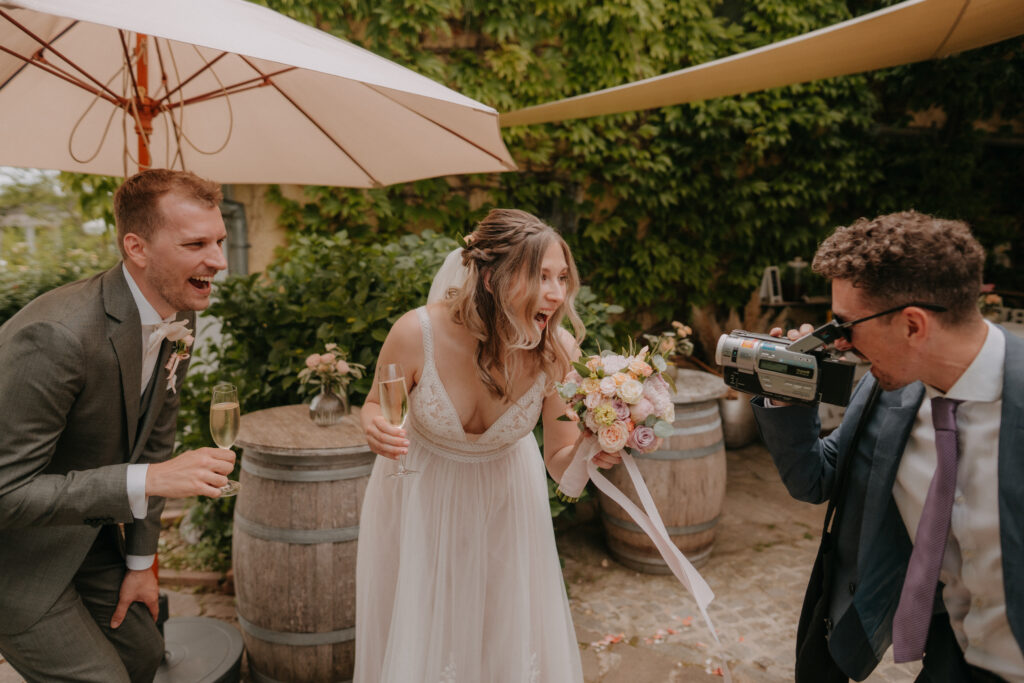 Fröhlicher Moment bei der Hochzeit – Braut und Bräutigam lachen gemeinsam beim Sektempfang, festgehalten in einer authentischen Hochzeitsreportage in der Steiermark