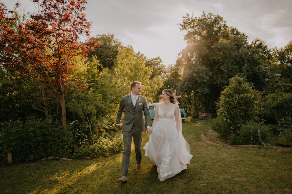 Brautpaar läuft lachend durch einen Garten bei Sonnenuntergang – natürliche Hochzeitsfotografie in der Steiermark von Pixellicious Fotografie