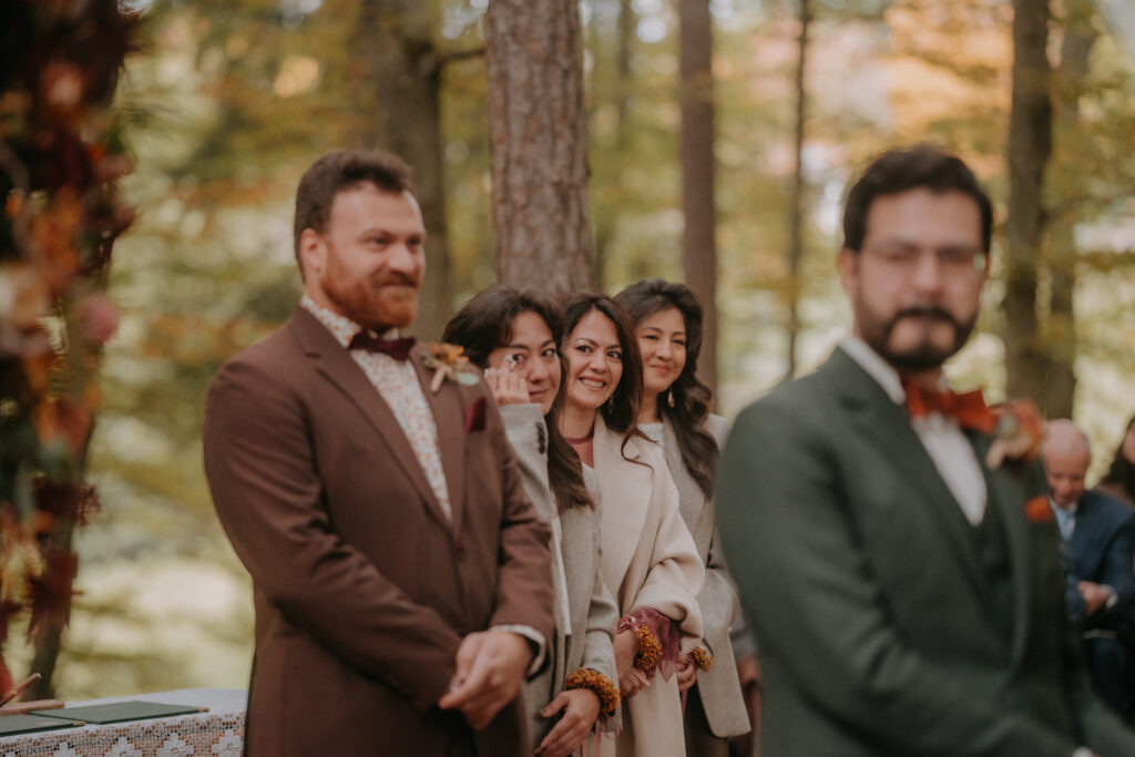 Gäste lächeln und wischen sich Tränen aus den Augen, während der Bräutigam vorne auf seine Braut wartet.