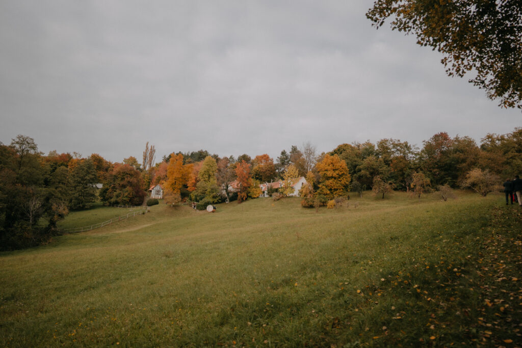 Weitblick über die herbstliche Hochzeitslocation in der Steiermark mit bunten Bäumen und Hofgebäuden in idyllischer Landschaft.