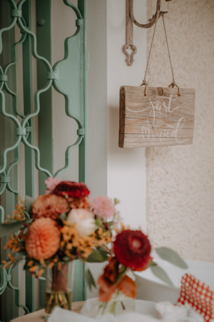 „Just Married“-Holzschild als Dekoration neben herbstlichem Blumenschmuck bei einer rustikalen Waldhochzeit in der Steiermark.