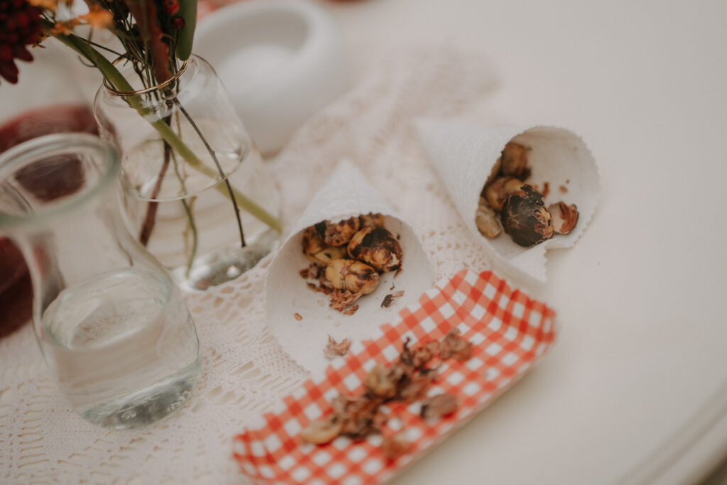 Kleine Papiertüten gefüllt mit gerösteten Maroni als herbstlicher Snack bei einer Waldhochzeit in der Steiermark.
