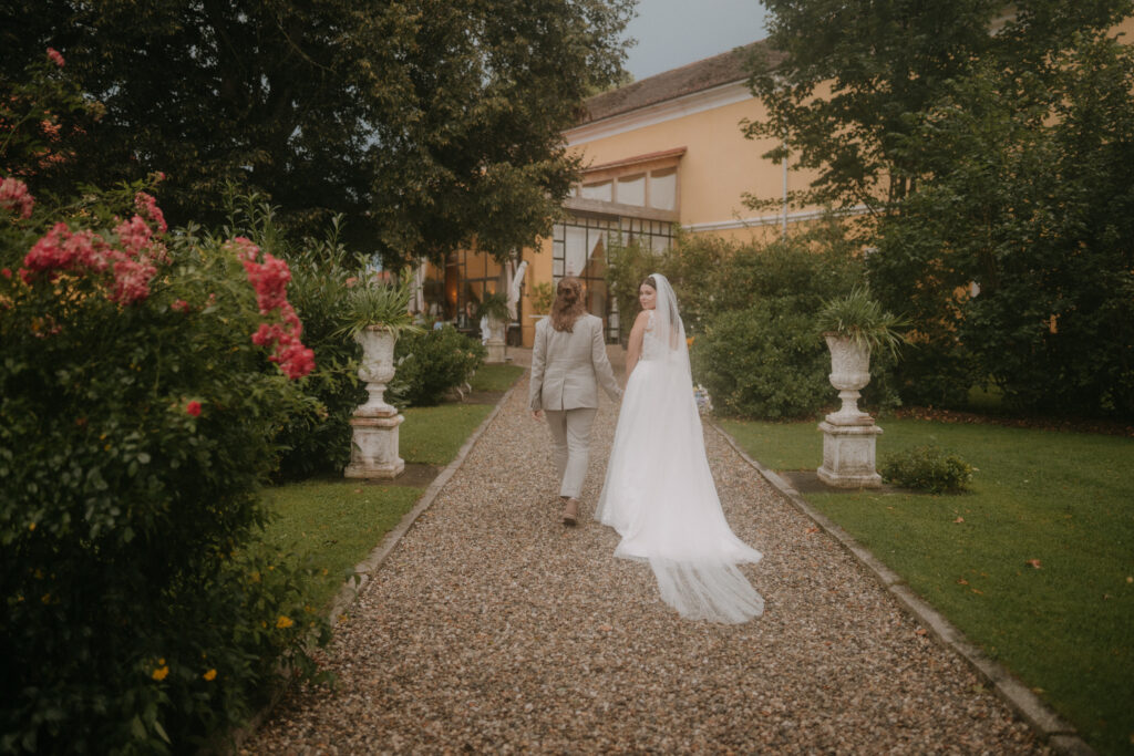 Brautpaar spaziert Hand in Hand durch den Rosengarten des Schloss Ottersbach – Hochzeit in der Steiermark, fotografiert von Pixellicious