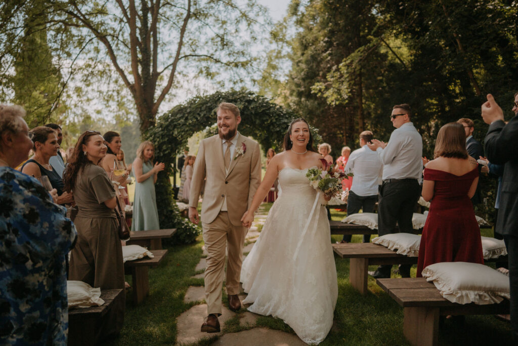 Brautpaar zieht hand in hand durch jubelnde Gäste nach der Trauung – Hochzeit Aiola im Schloss Graz