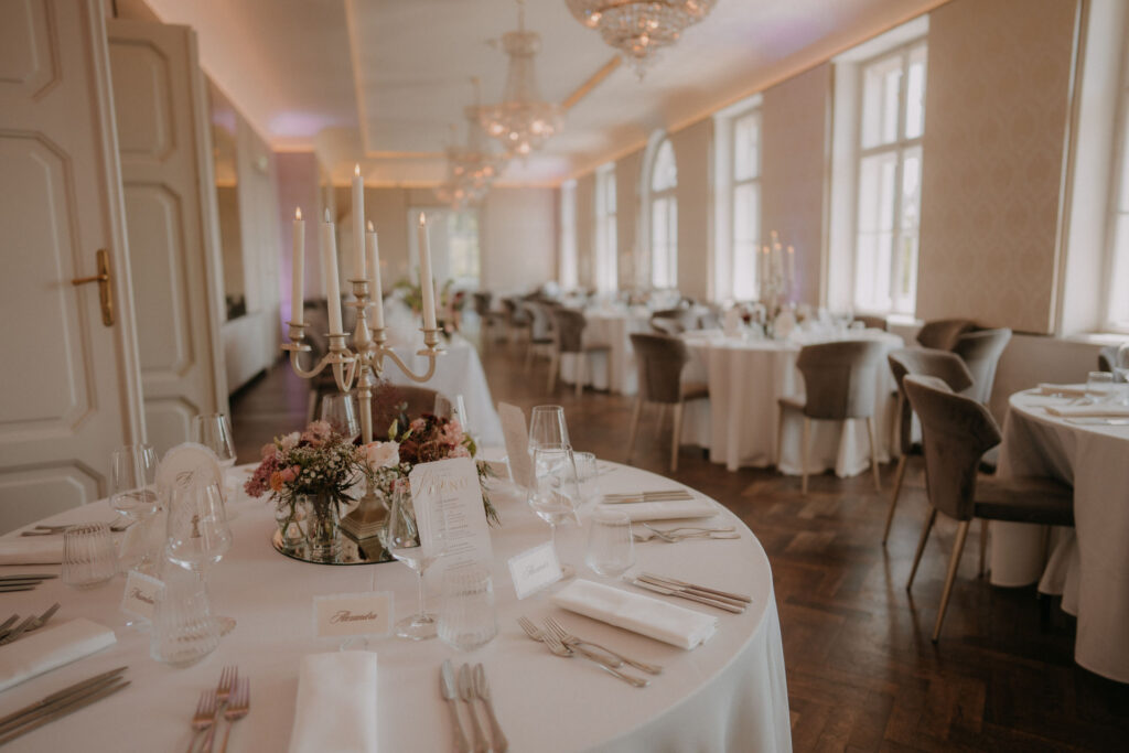 Festsaal im Aiola im Schloss Graz mit weißen Tischdecken und Kerzenleuchtern