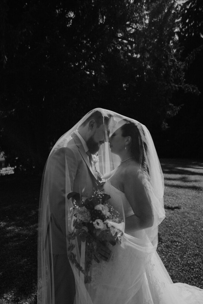 Brautpaar küsst sich unter Schleier – Schwarzweißfoto Hochzeit Graz