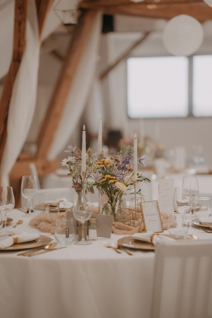 Gedeckter Hochzeitstisch mit Kerzen, Blumen und Menükarte