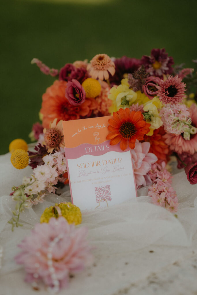 Bunter Brautstrauß mit Dahlien und Ringelblumen neben der Einladungskarte 'Seid ihr dabei?' auf Schloss Ottersbach