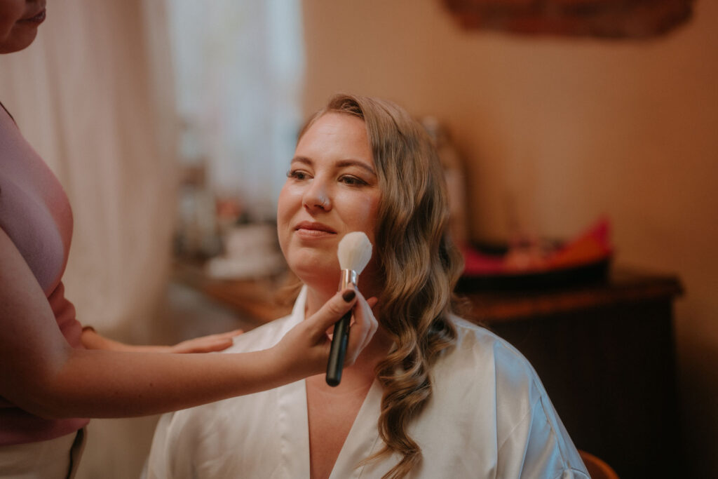 Braut bekommt beim Getting Ready ihr Make-up aufgetragen auf Schloss Ottersbach