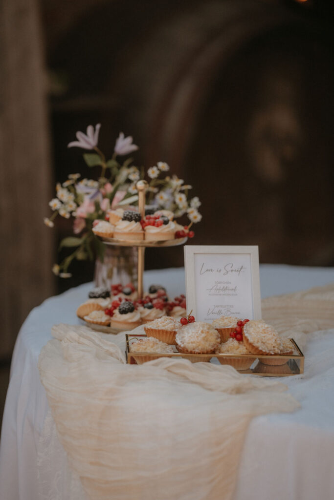 Etagere mit Beeren-Cupcakes und Wildblumen am Dessertbuffet