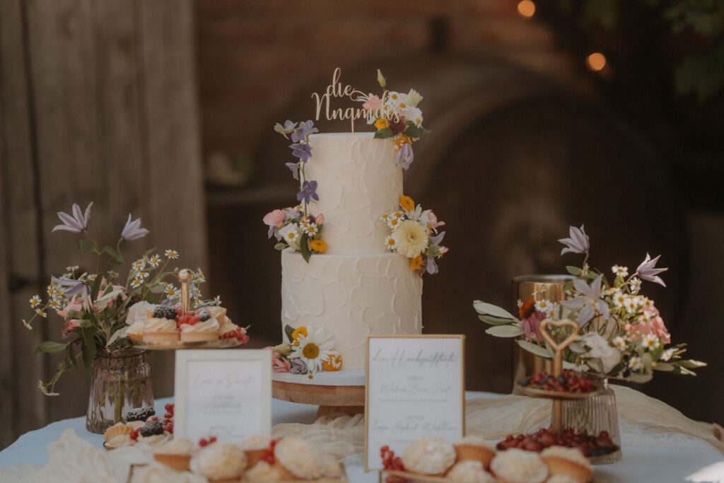 Zweistöckige Hochzeitstorte mit essbaren Blüten und Namens-Cake-Topper