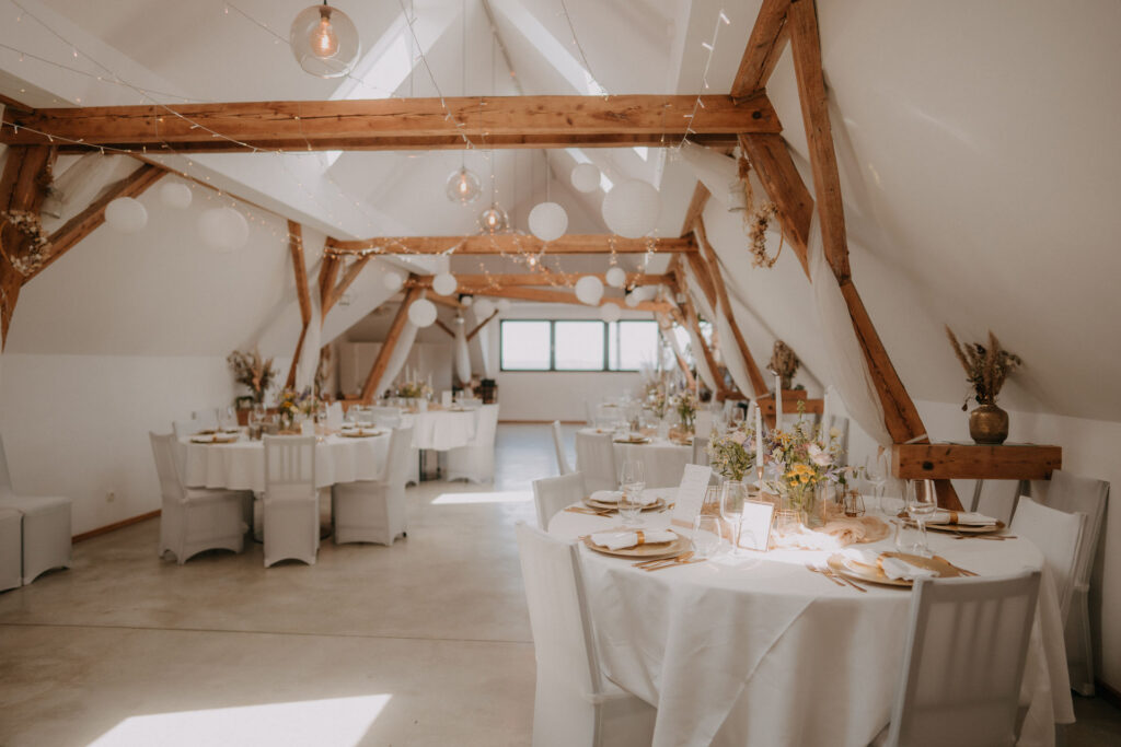 Hochzeitstafel mit Papierlaternen im lichtdurchfluteten Scheunengebäude