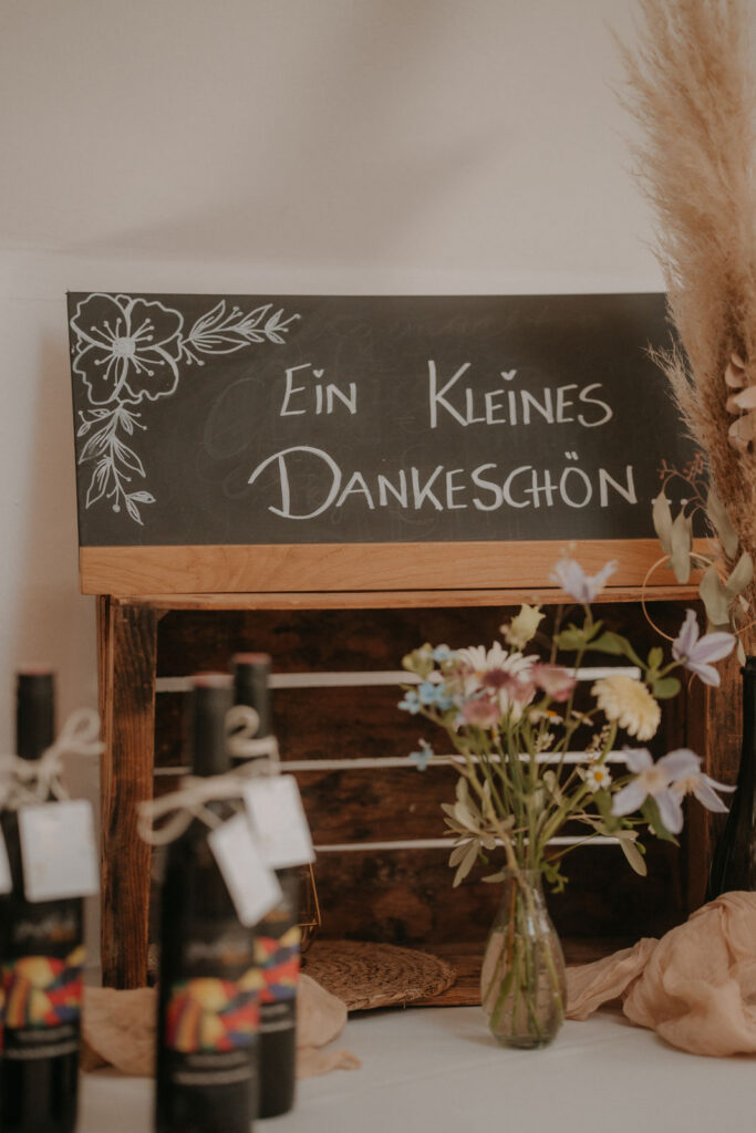 Gästegeschenke mit Weinflaschen und Blumen unter Tafel