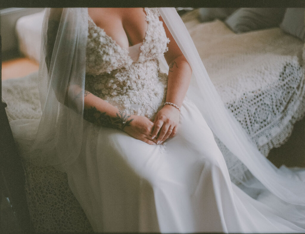 Analoge Detailaufnahme von Brautkleid und gefalteten Händen bei der Hochzeit auf Schloss Ottersbach