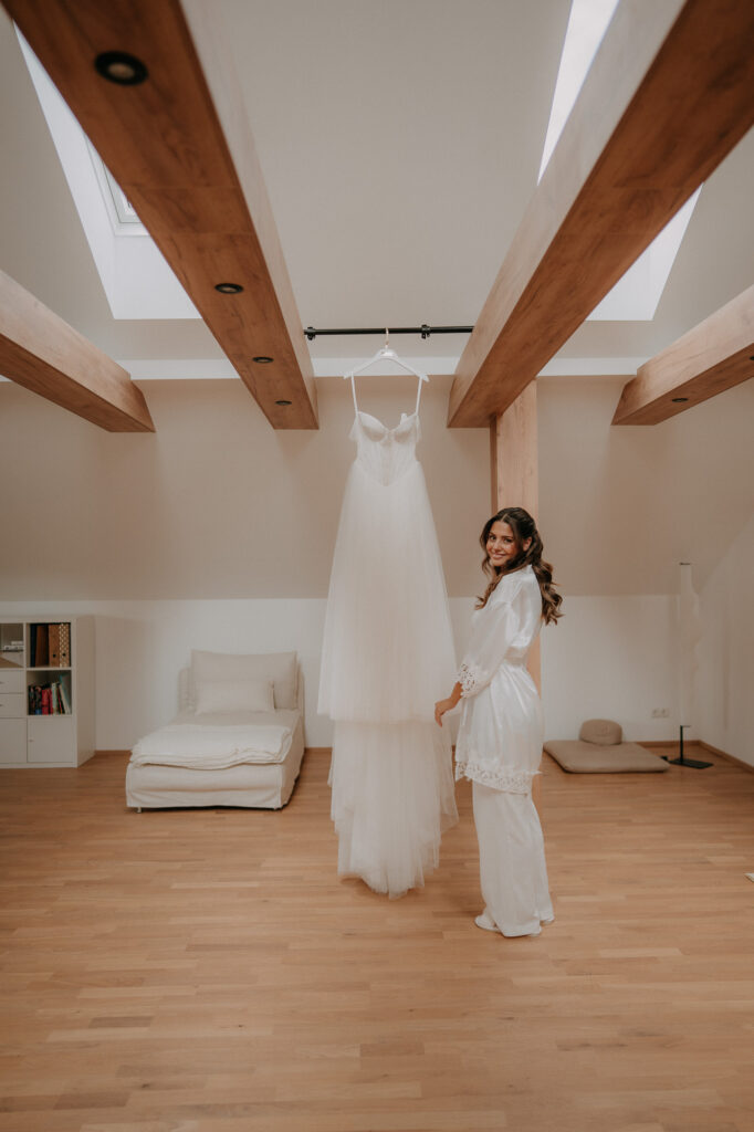Brautkleid hängt im hellen Zimmer des Weinberghauses
