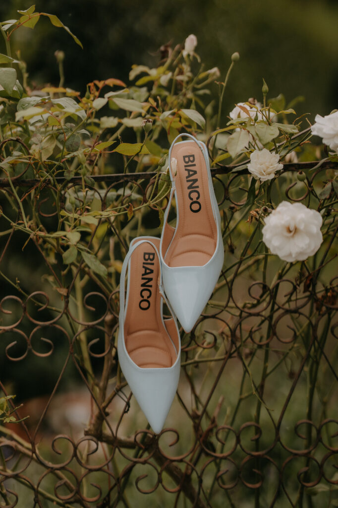 Hellblaue Brautschuhe an einem Rosengitter