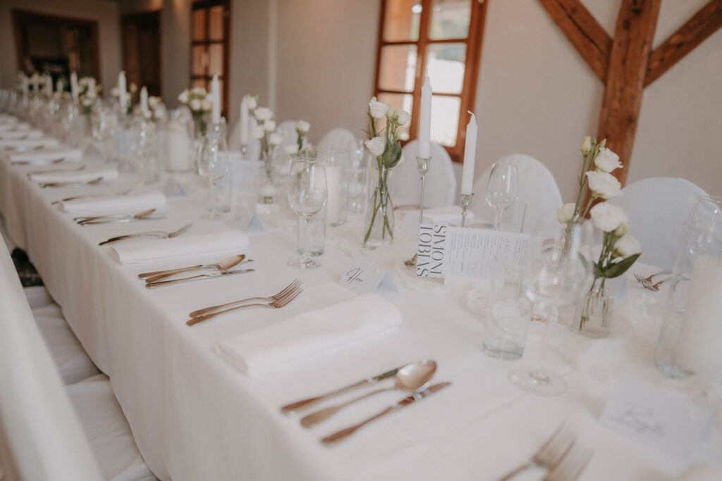 Weiß gedeckte Hochzeitstafel im Festsaal am Hochzeitsweingut Kranachberg