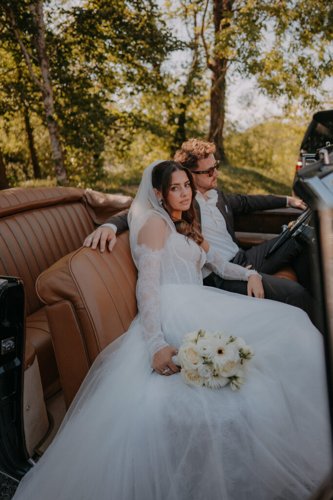 Braut mit Brautstrauß im Oldtimer-Cabrio
