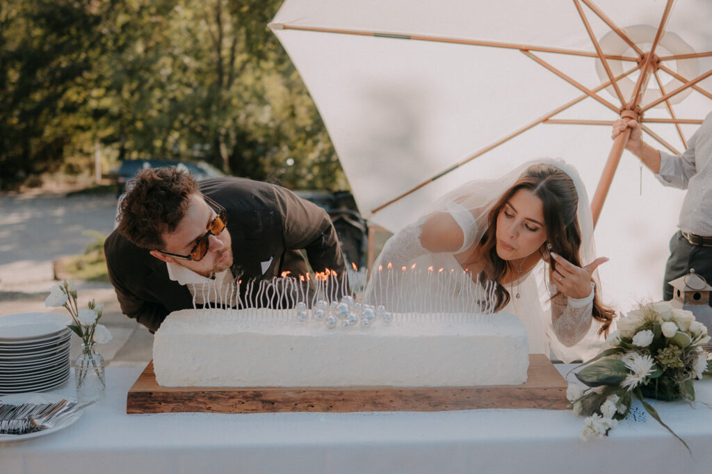 Brautpaar pustet die Kerzen auf der Hochzeitstorte aus