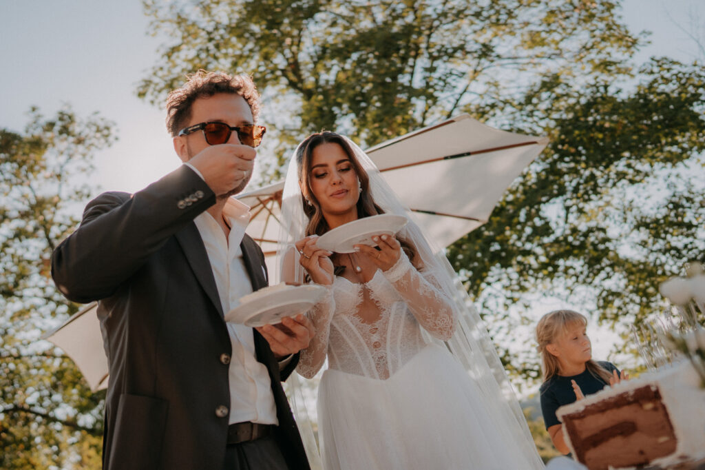 Brautpaar probiert die Hochzeitstorte im Garten
