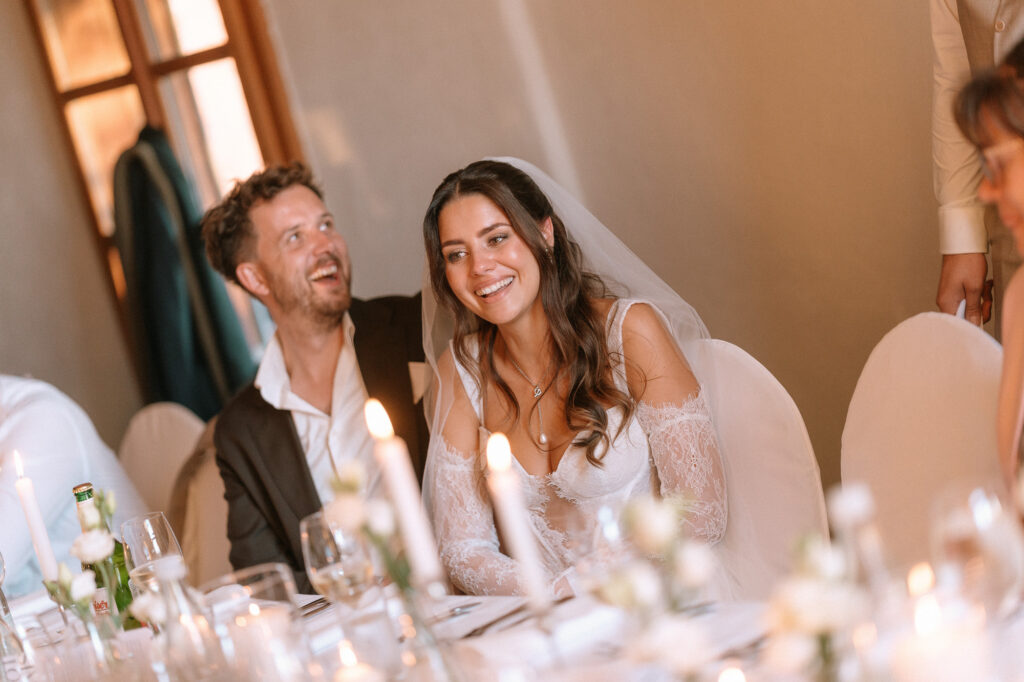 Brautpaar lacht beim Dinner an der Hochzeitstafel